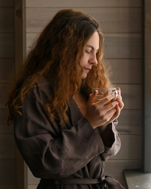 a woman with curly hair holds her hand to a glass and is looking down