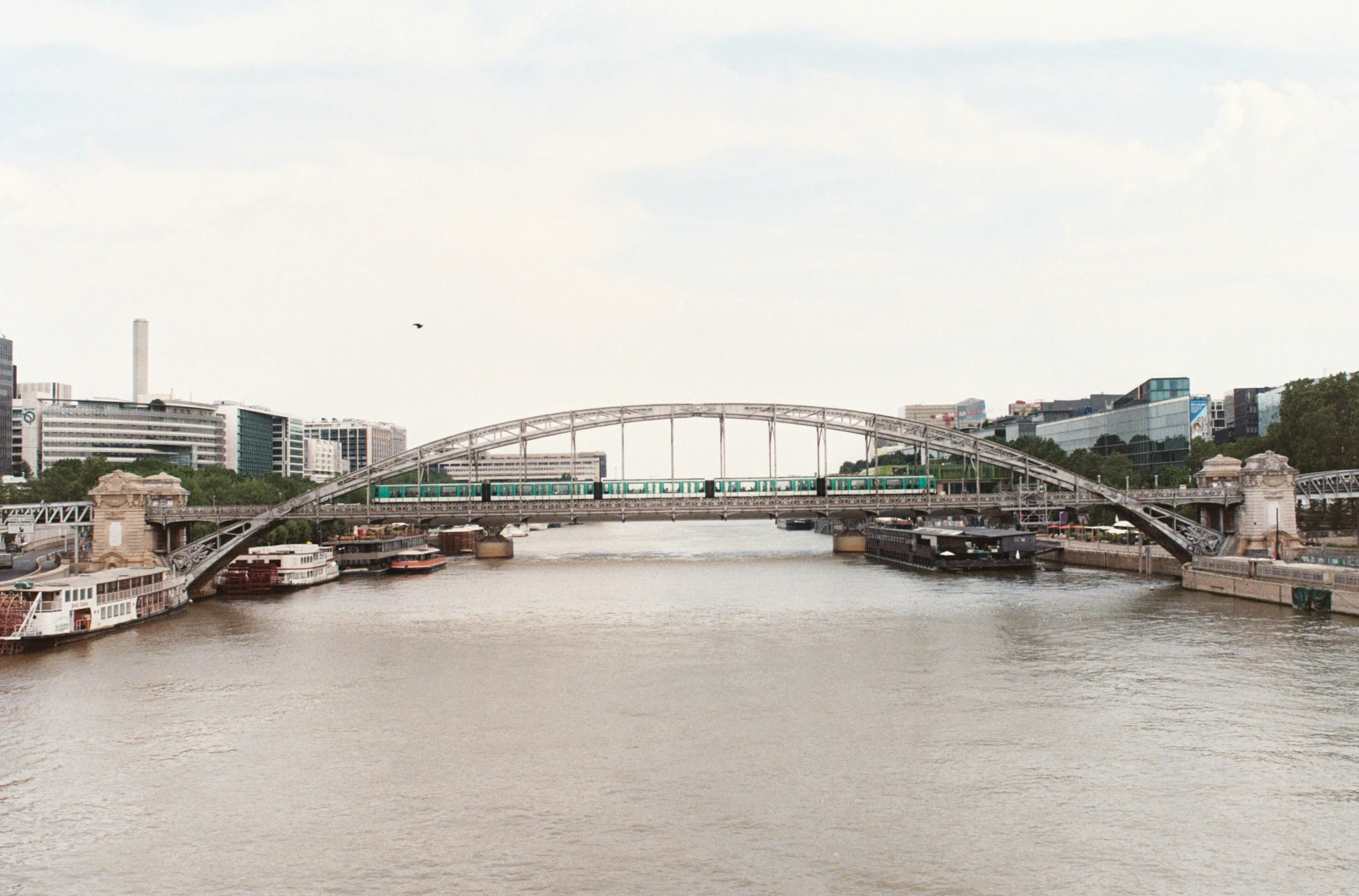 a view of an overhanging bridge next to a river with docked boats