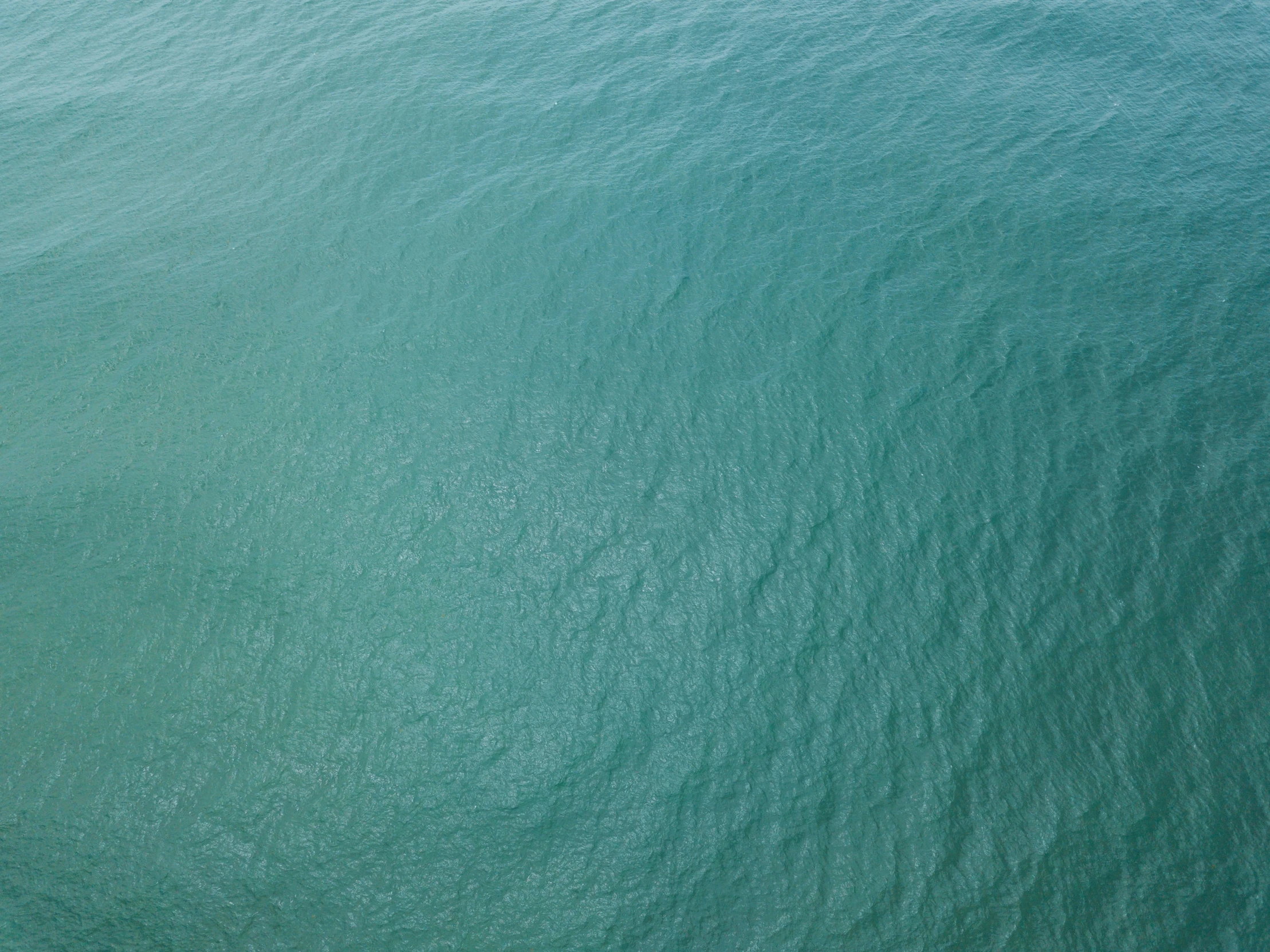 an aerial view of green water and boats