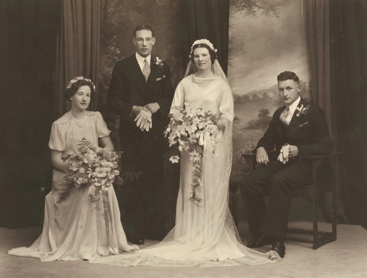 a man and woman wearing wedding clothes, surrounded by two other women and one gentleman