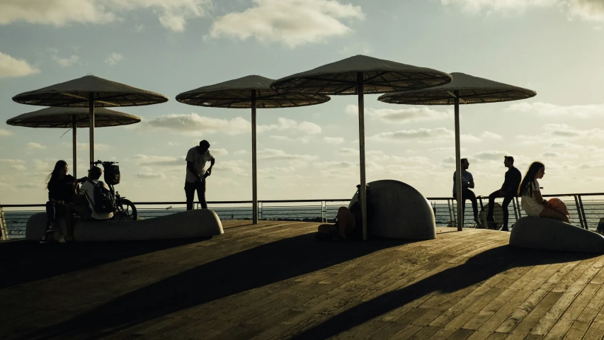 a group of people standing on top of a pier under umbrellas