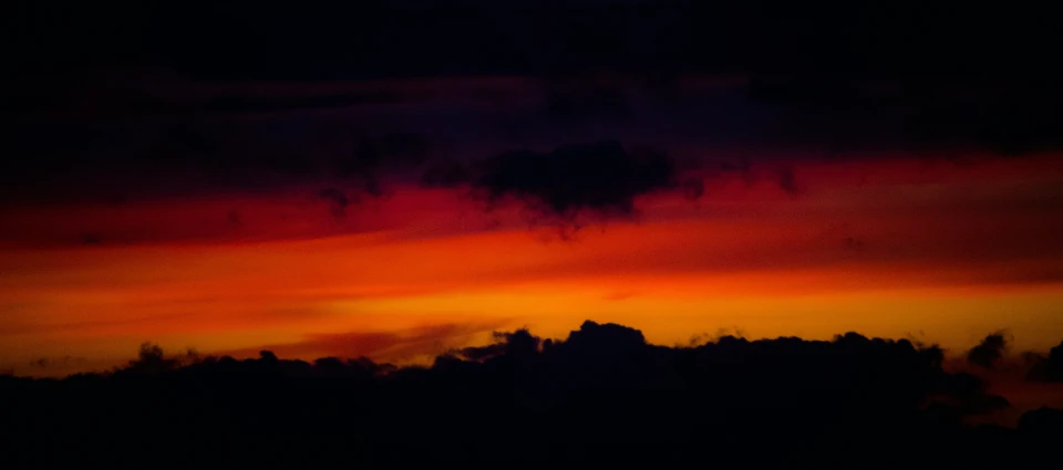 some birds flying through a colorful sky with clouds