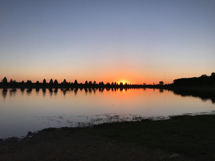 a beautiful sunset with many trees reflected in the water