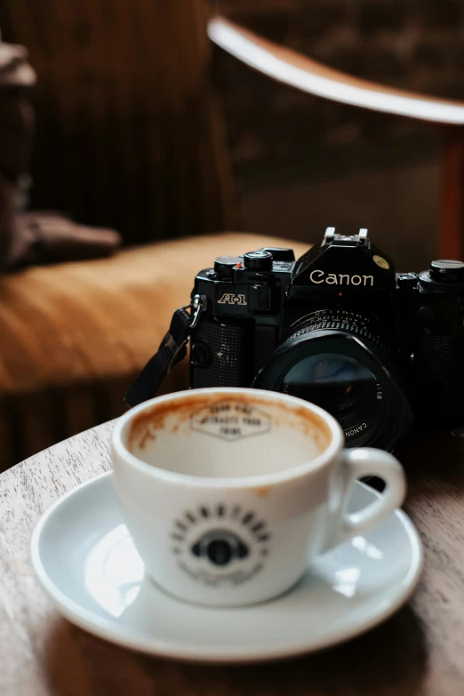 a camera, cup, and saucer on a wooden table