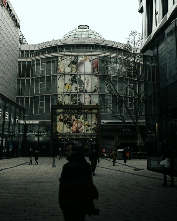 people walking on the street in front of a glass building