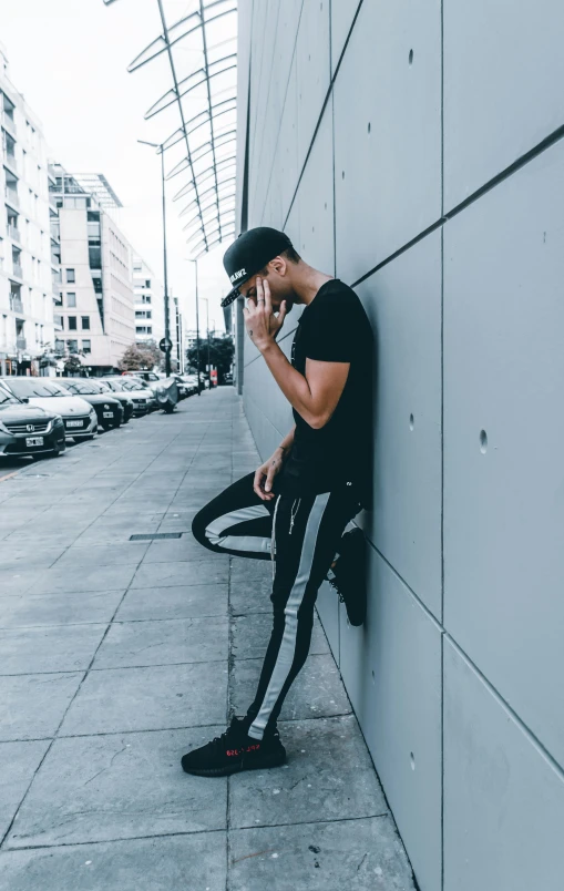 a man on his cellphone leaning against a wall