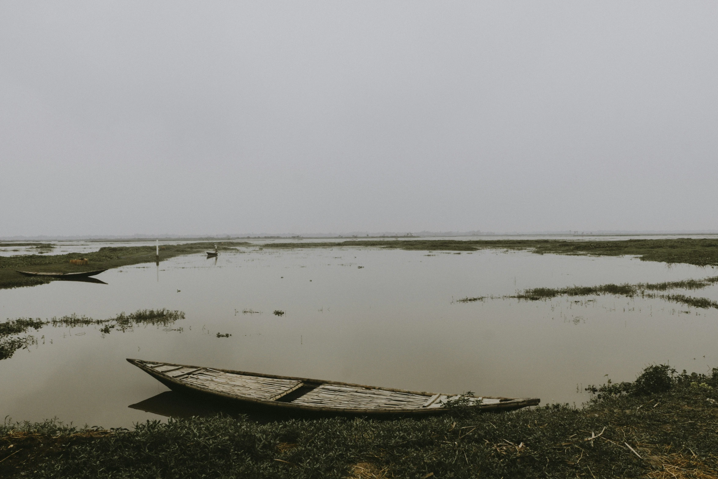 a boat sitting on top of a river near the shore