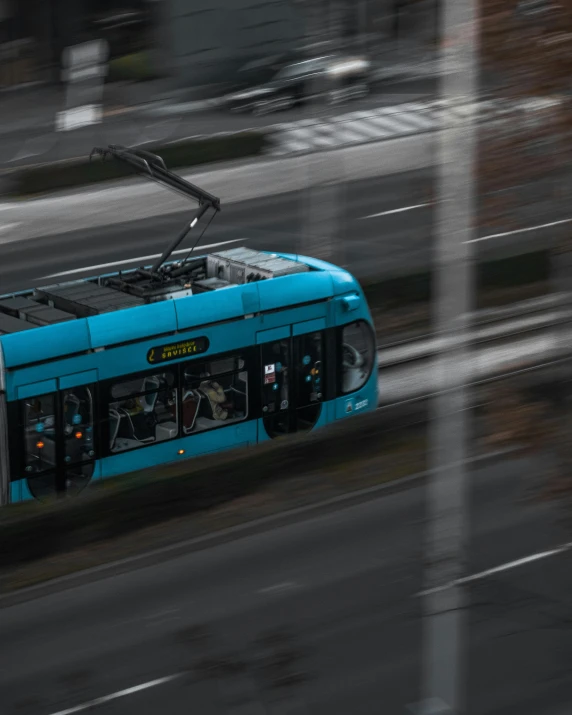 a blue trolley in the city moving through the streets