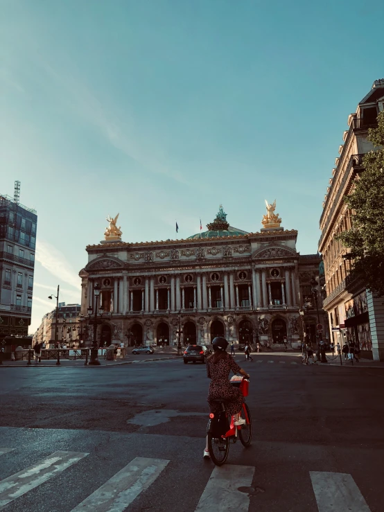 a man riding a bike past a building in a city