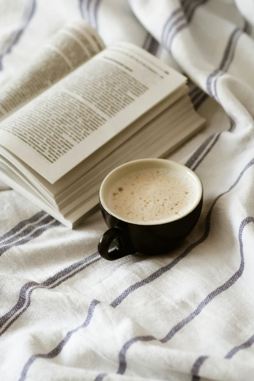 a coffee cup with cappuccino next to a stack of books