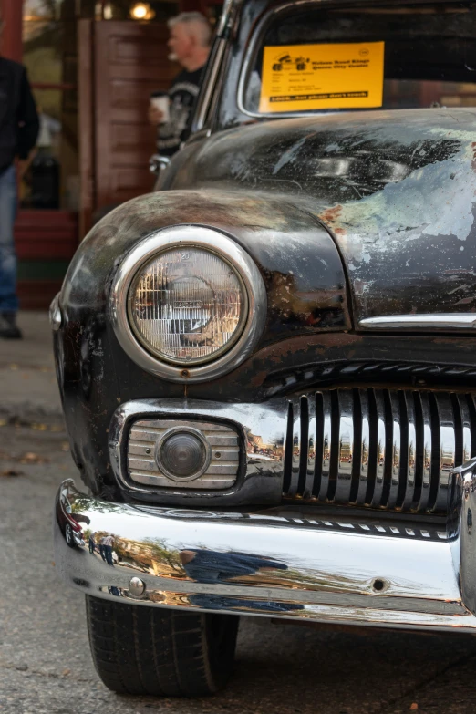 the front of a black antique car parked in a parking lot