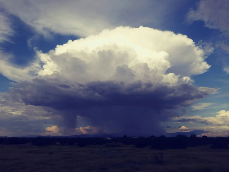 clouds are floating in the sky above a plain