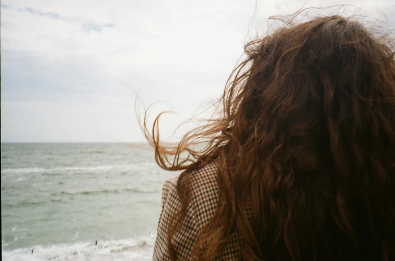 closeup of female hair and the ocean in the background