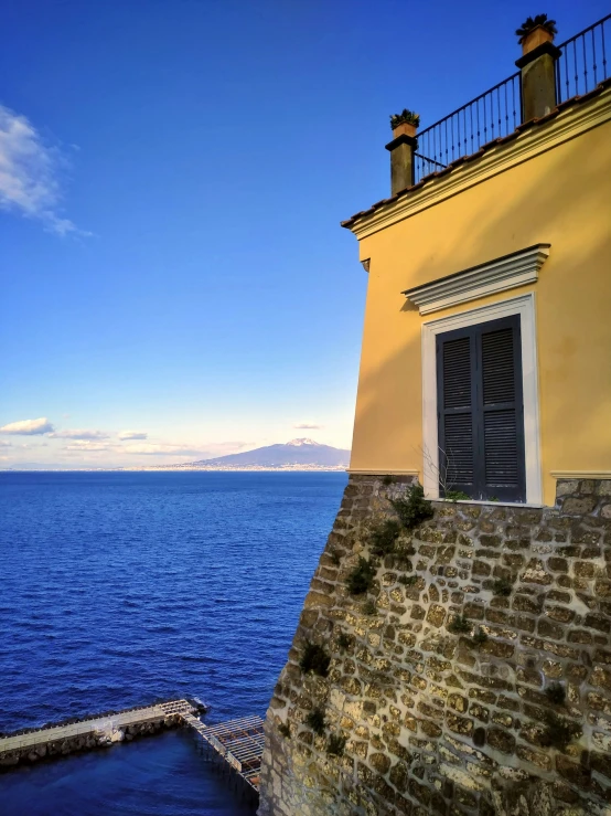 an old building with an open window overlooks the ocean