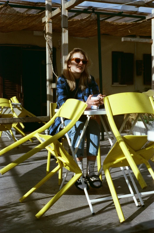 a woman sitting at a table in front of a set of yellow chairs