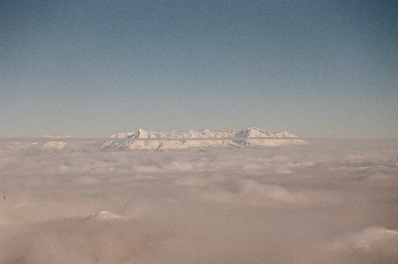 snow capped mountains from an airplane looking out on clouds