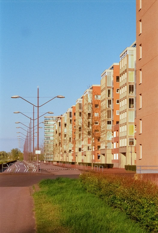 a street lined with tall brown buildings sitting next to green grass