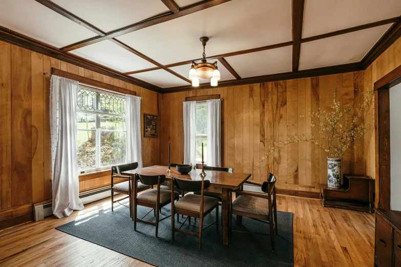 a wood paneled dining room with a rug and chairs