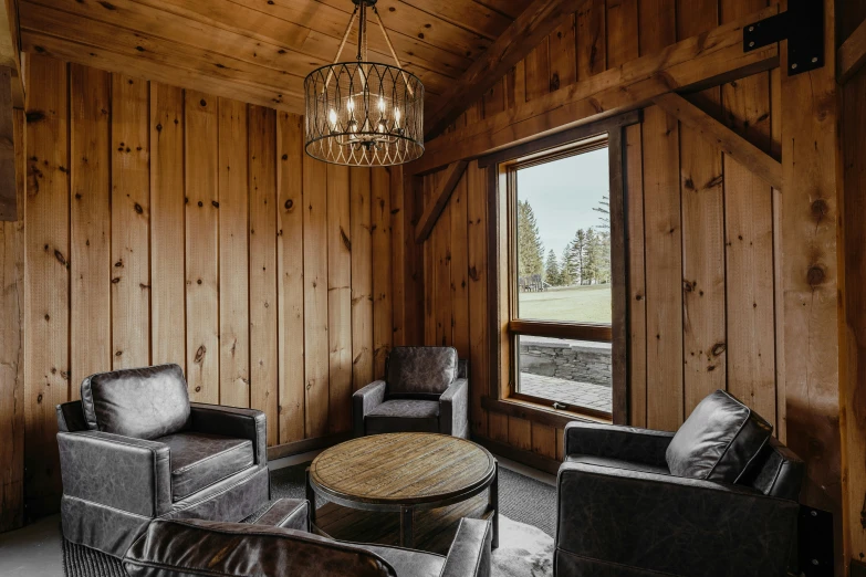 the living room in a cabin has wooden paneling