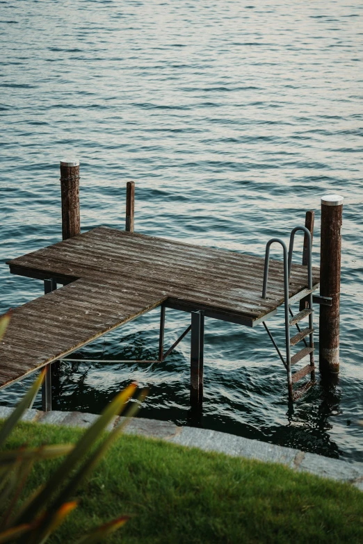 there is a dock on the water and grass in front of it