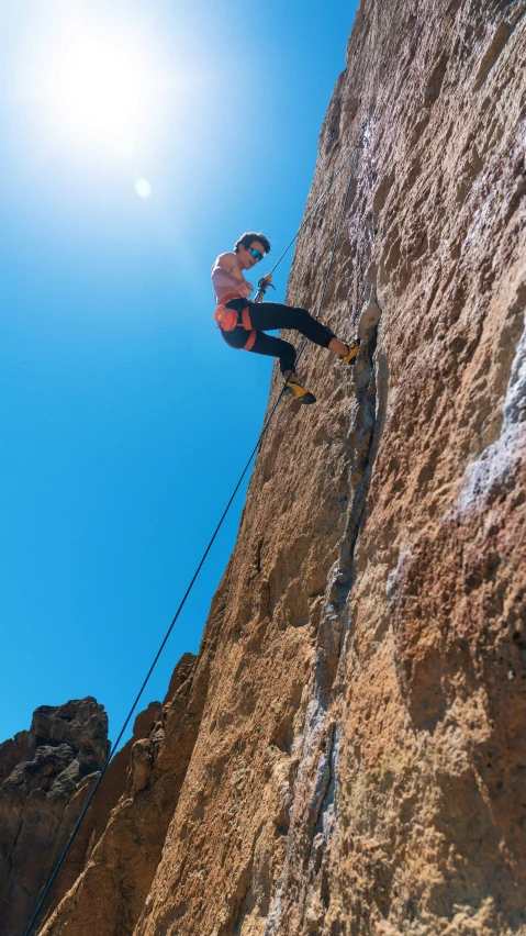 a man climbing a rock up the side of a mountain