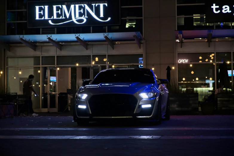 a car is parked in front of a neon lit el