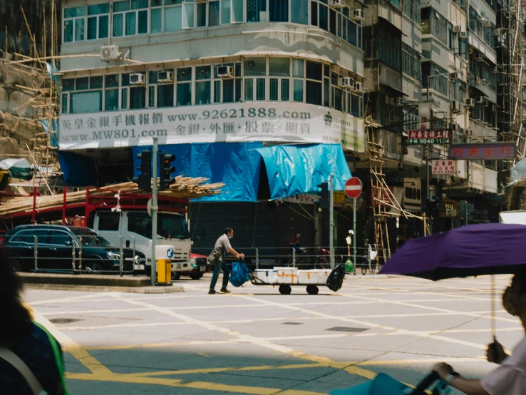 two people and a woman cross the street with an umbrella