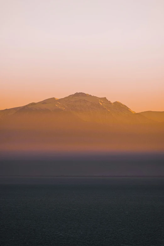 a hazy sky with a mountain and sea