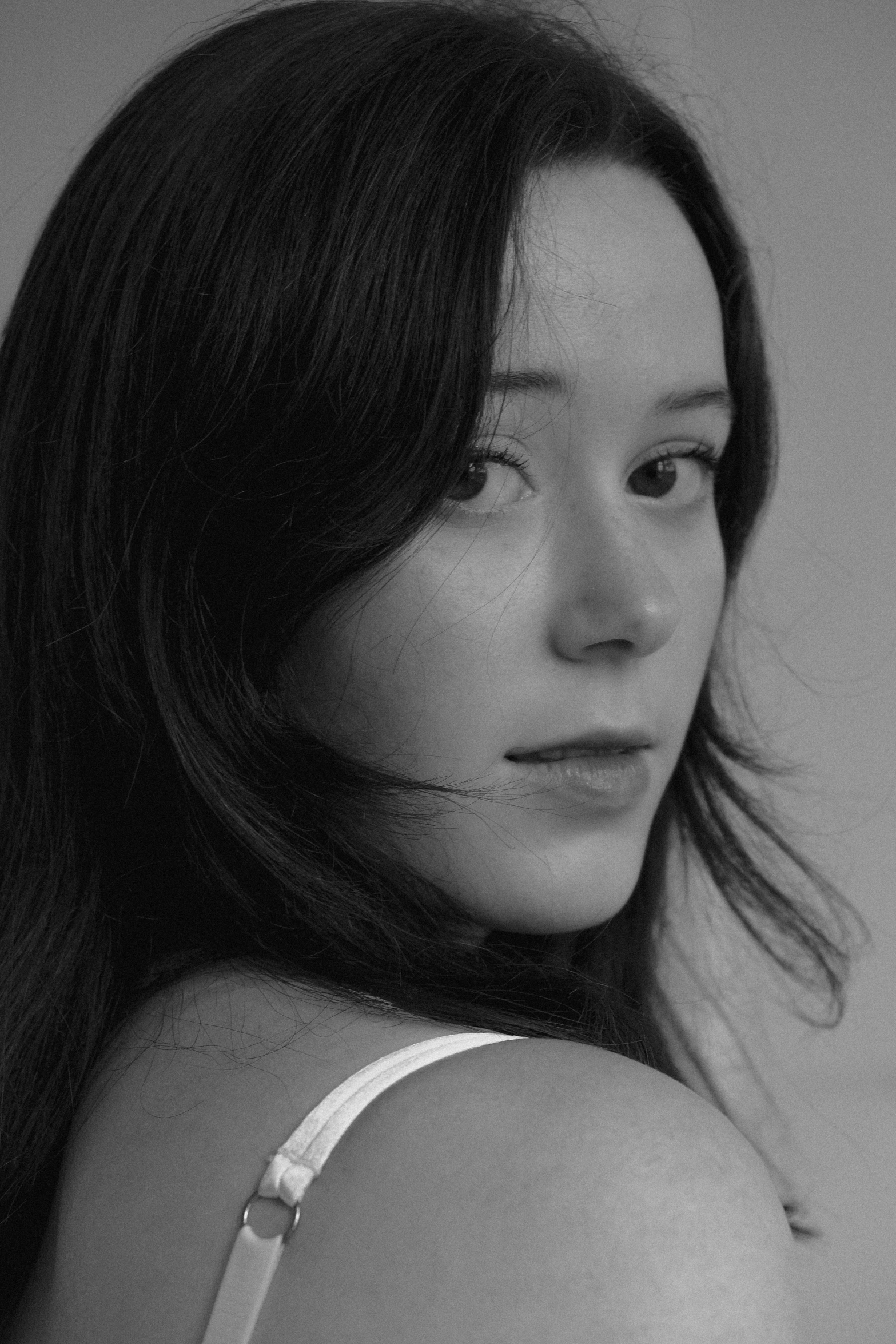 a woman with long hair and wearing an undershirt, poses for a portrait