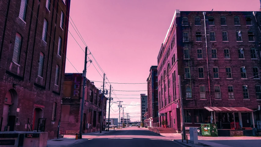 the sky is bright pink above old buildings on a street