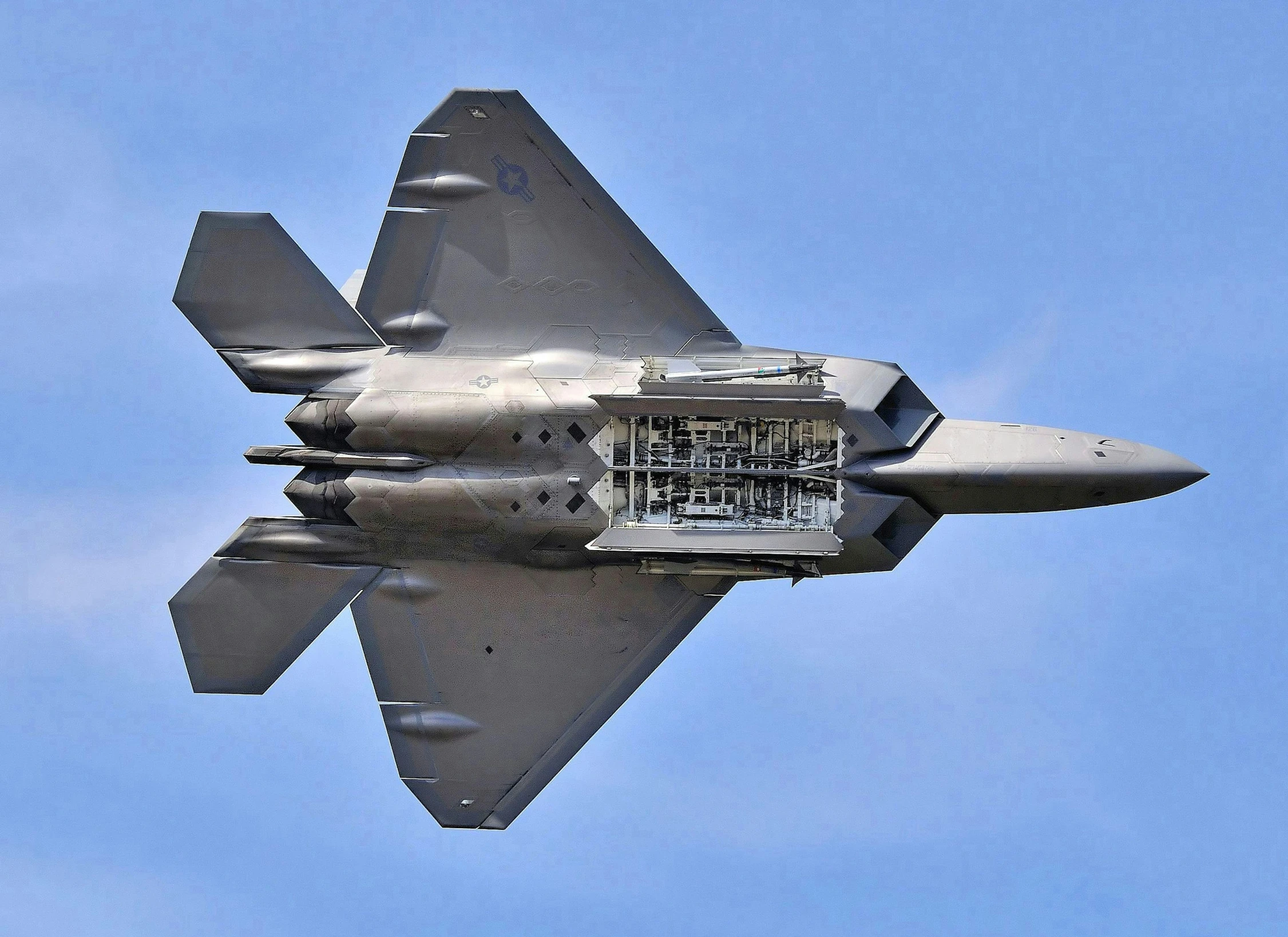 a silver fighter jet is flying through the blue sky