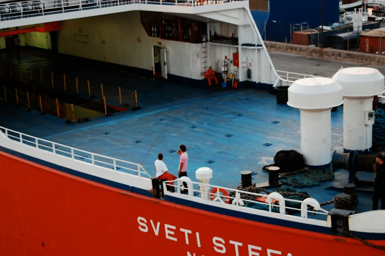 a red and white ship and some people standing around