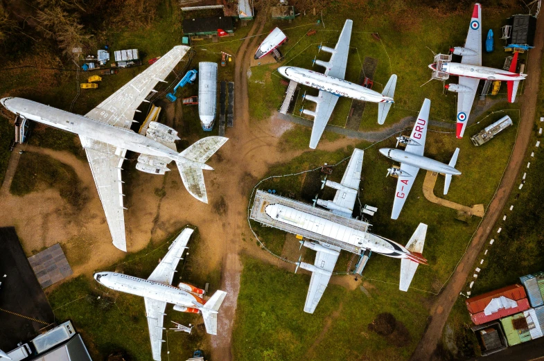 a variety of large airplanes sitting next to each other on a lush green field