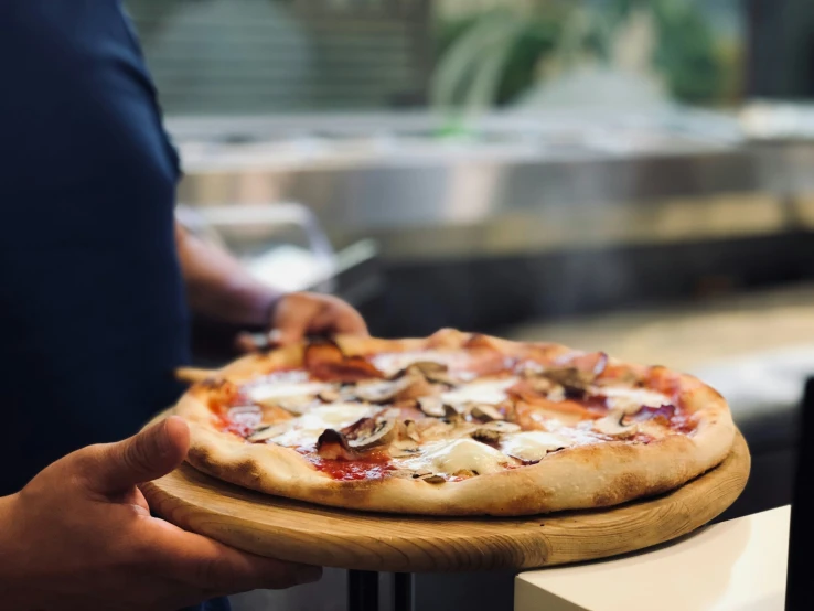 there is a man holding a pizza on a wooden plate