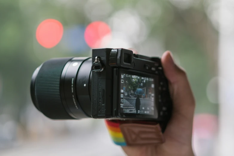 a hand is holding a camera with a view of the street