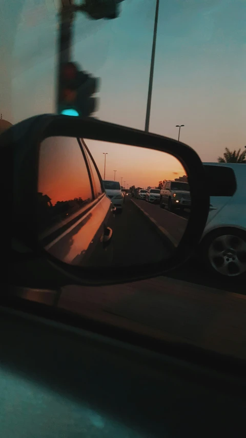 a rear view mirror on a vehicle with a sunset in the background