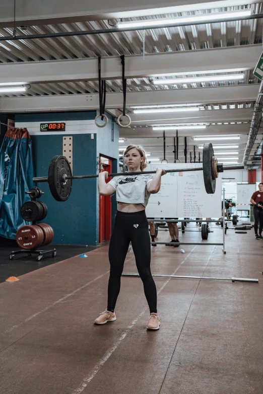 a woman is standing in the middle of a gym lifting a bar