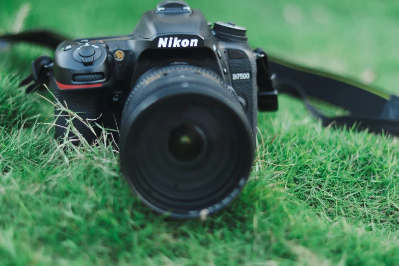 a nikon camera with its lens showing and in the grass