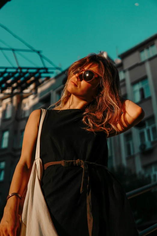 a young woman with dark glasses standing in the sun