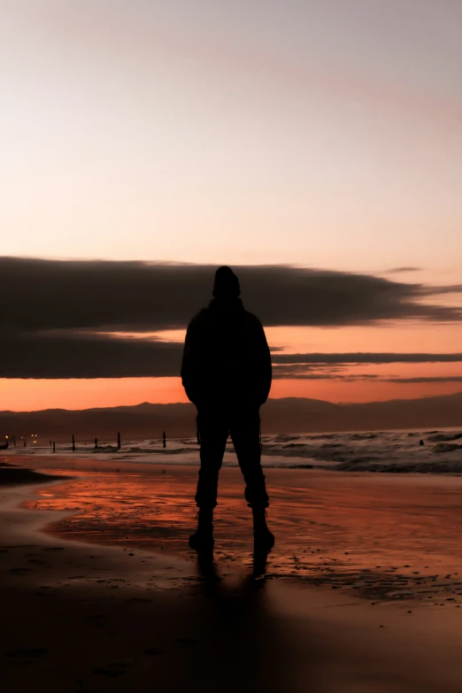 a person stands at the edge of the water as the sun sets