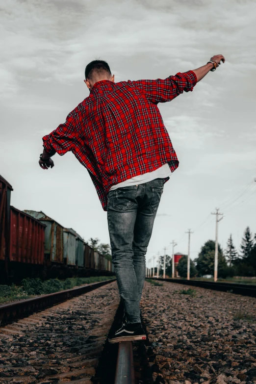 a young man is skateboarding across the railroad tracks