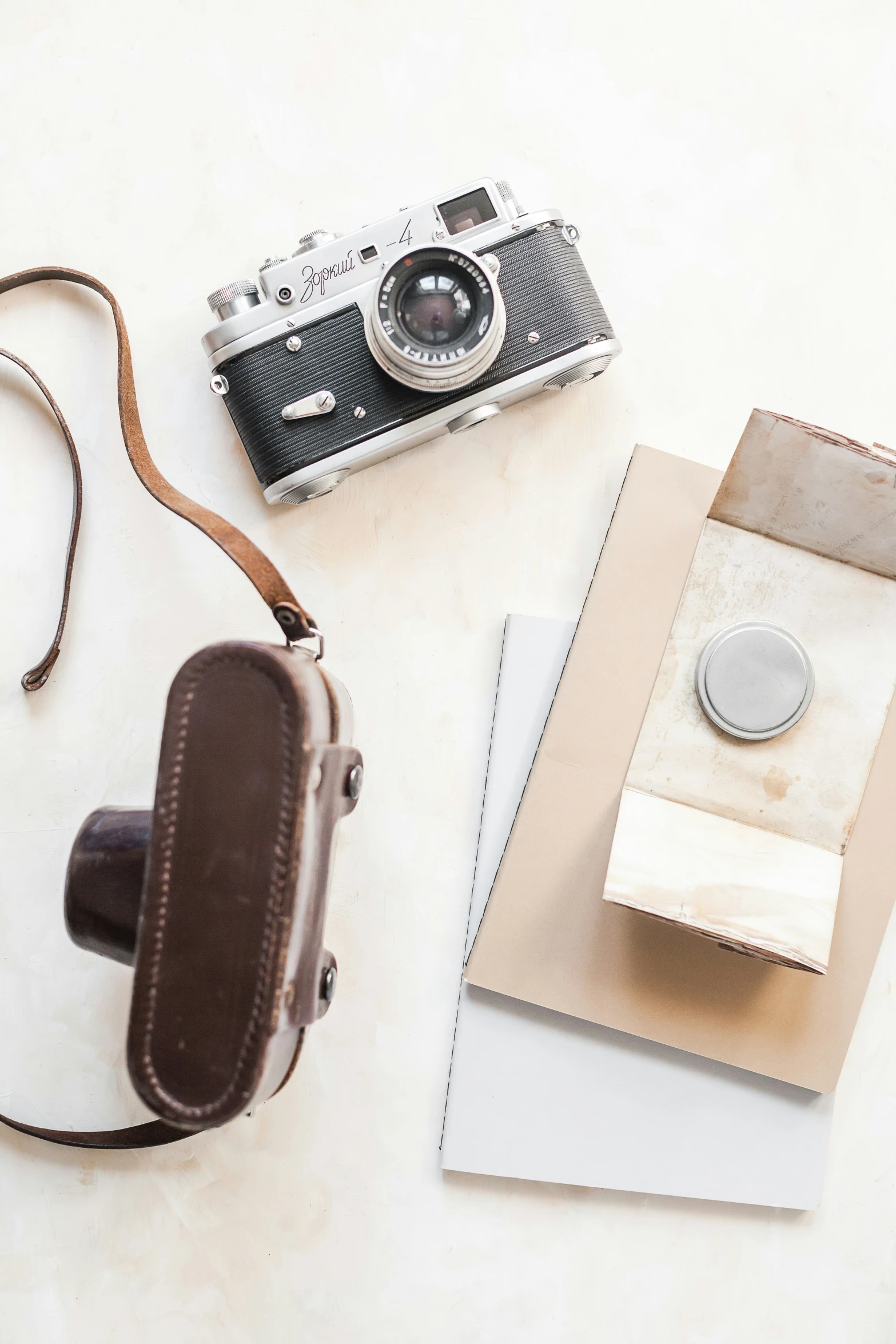 a old camera, some papers and a book on a white table