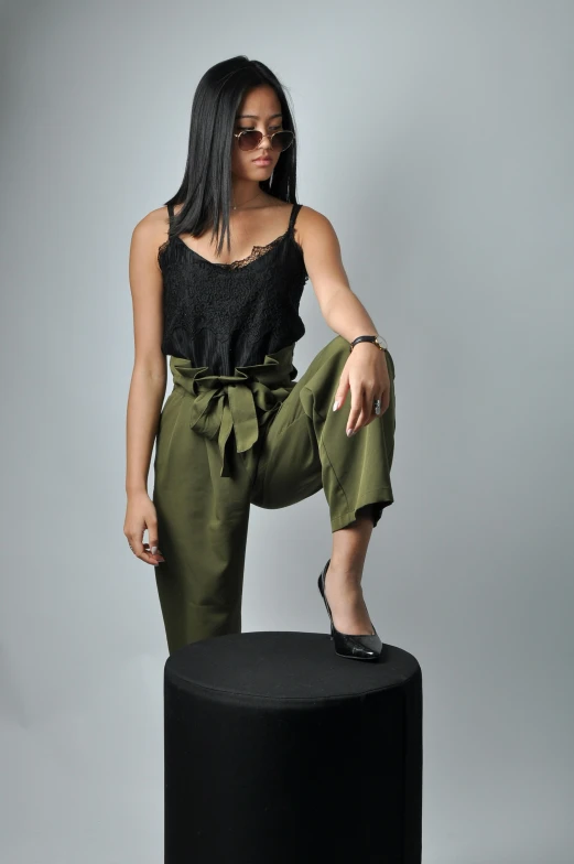 a woman in a black top and green pants