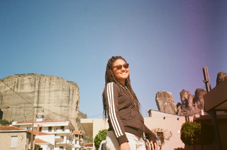 a woman is standing with a rock in the background