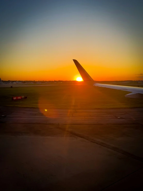 the sun is rising behind an airplane on a runway