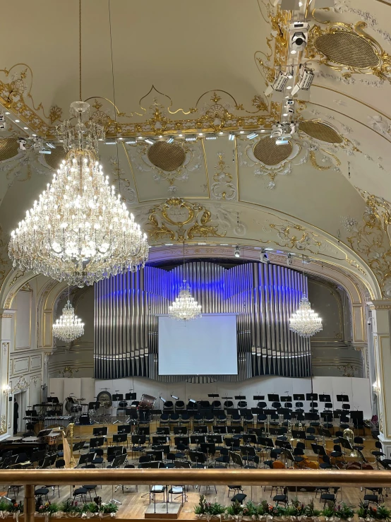 a fancy auditorium with chandelier lights and a projection screen