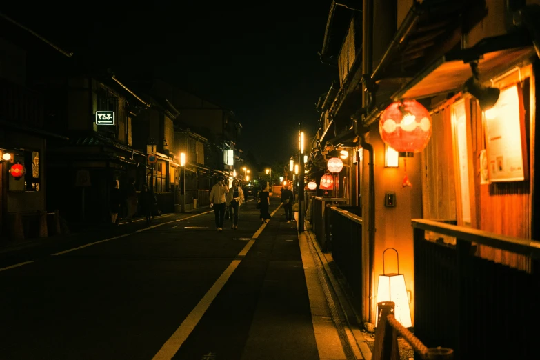 a small town street at night with light on and some people standing