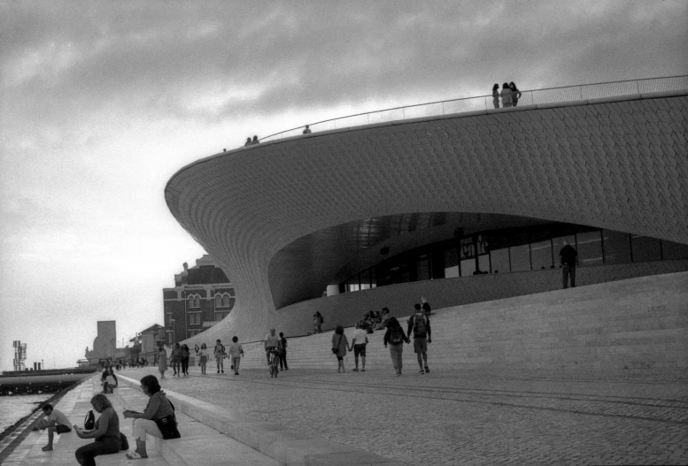 people walking and sitting on steps near a building