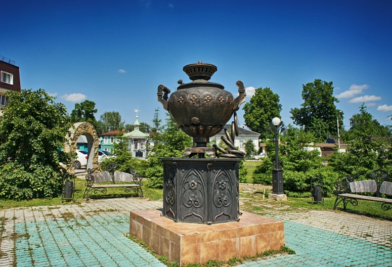 the view of an old vase statue in the middle of a park