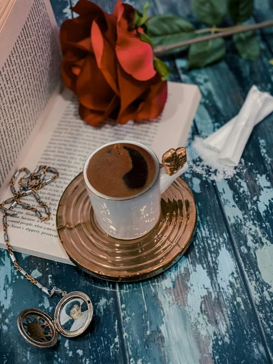 a cup of  chocolate is on the table next to a book